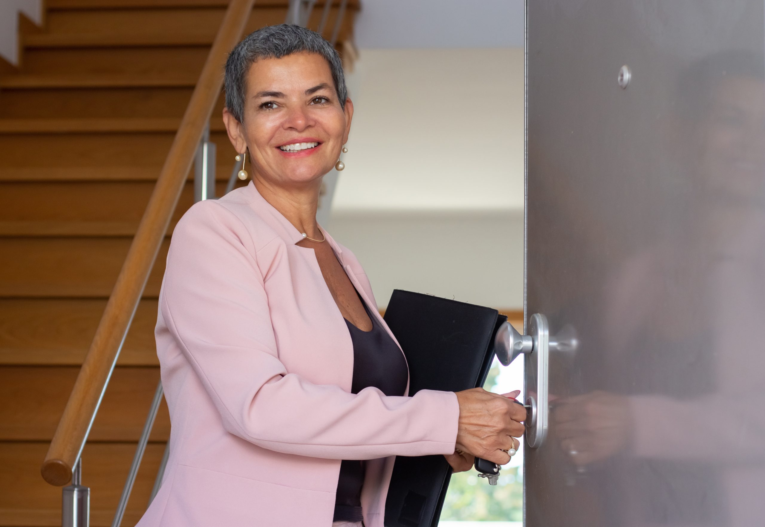 Portrait of welcoming real estate agent at house entrance